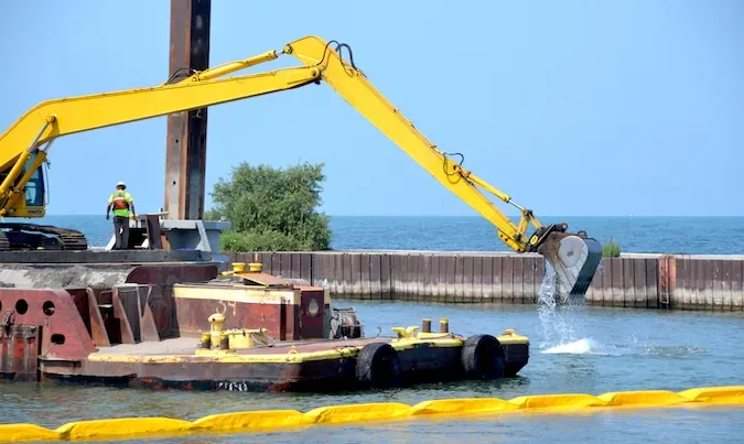 Excavator performing dredging work over water